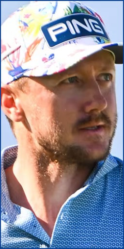 A man wearing a floral-patterned cap and a blue collared shirt gazes thoughtfully