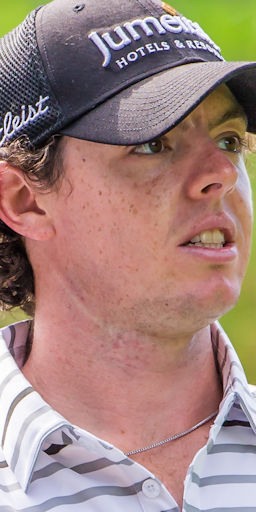 A focused golfer, wearing a black cap and a striped shirt, displays intense concentration during a tournament.